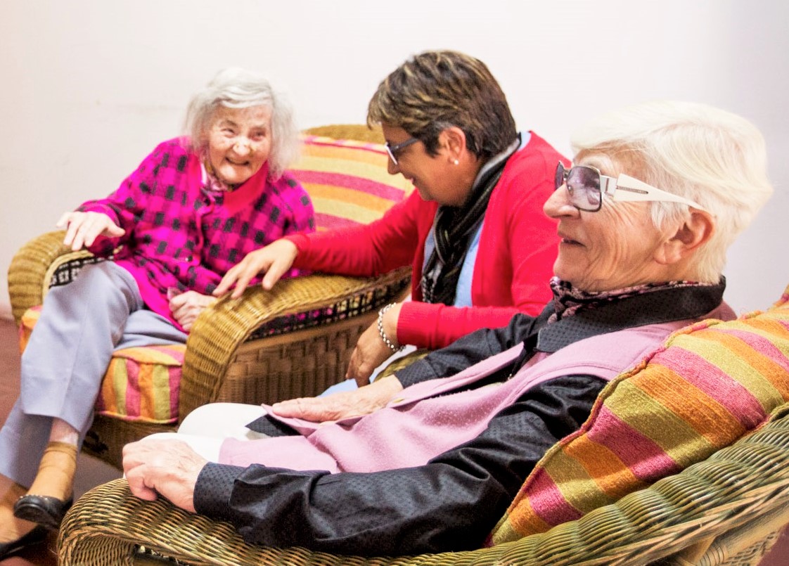 Tres adultas mayores sentadas en un sillón. 