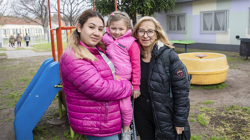 Una niña con su madre y su abuela están mirando a cámara mientras disfrutan de la actividad realizada en el predio donde se hizo el Día Nacional del Derecho a la identidad.