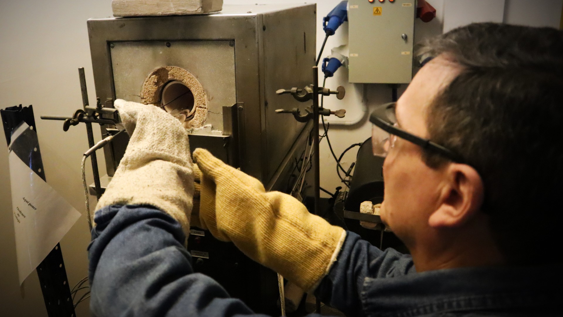 Tecnólogo inserta probeta de metal a horno para ensayos