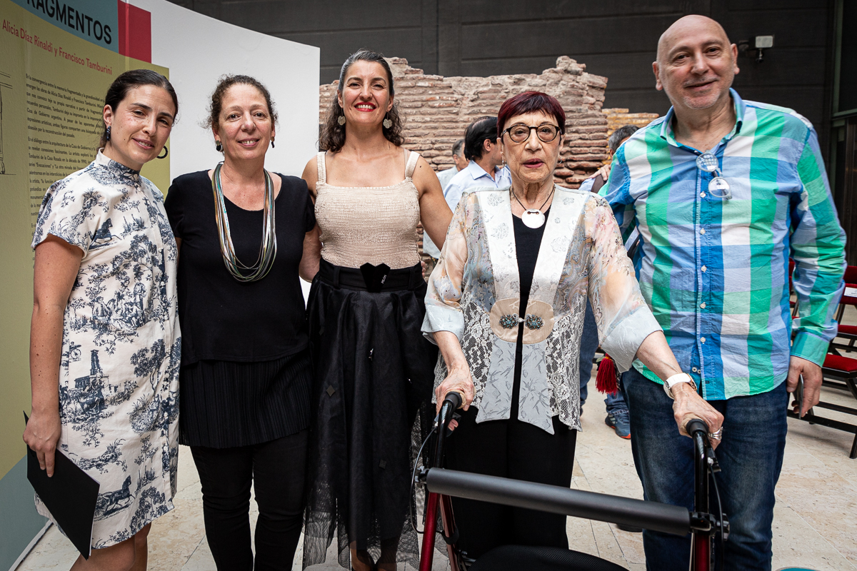 La imagen muestra a cinco personas posando para una foto. Están en un ambiente interior. Todos están sonriendo.