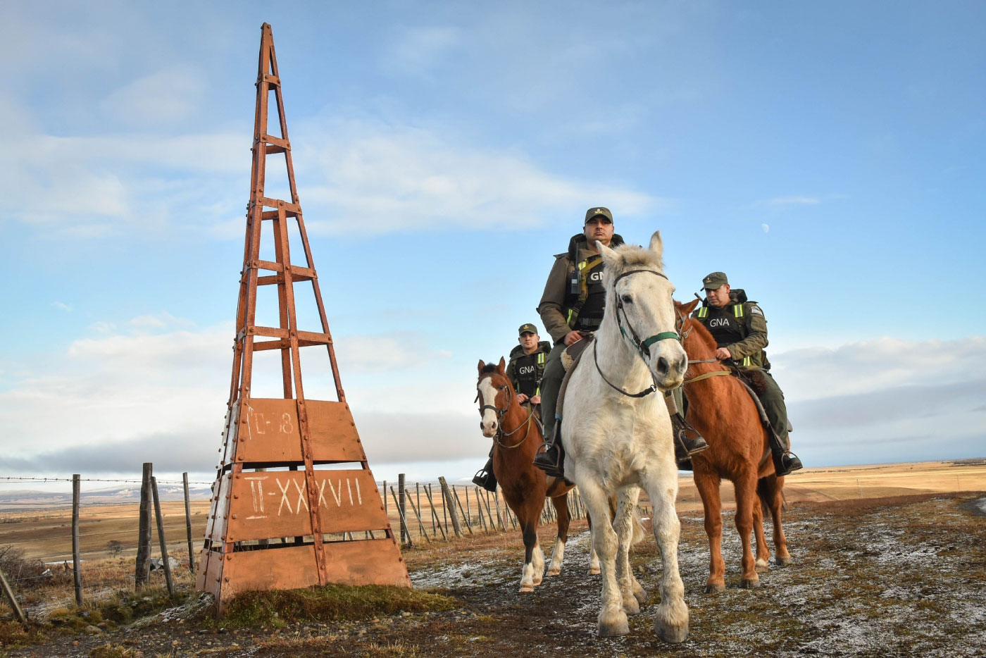 Gendarmes a caballo frente a un hito fronterizo
