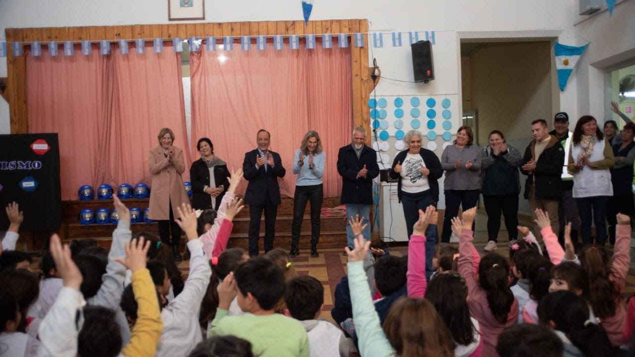 Funcionarios y capacitadores saludan desde el escenario a estudiantes en el marco de una jornada de capacitación en seguridad vial.