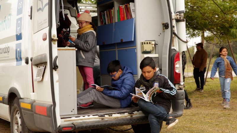 Tres niños leyendo dentro de la bibliomóvil.