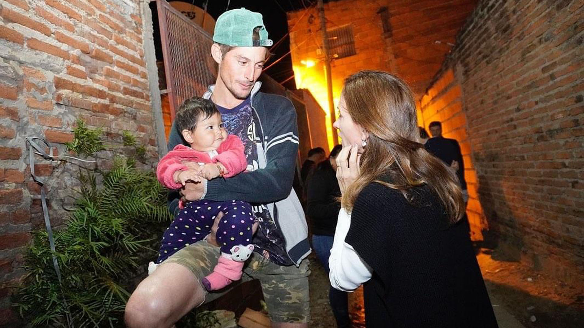 La ministra hablando con un hombre que tiene a si pequeña hija en brazos en uno de los barrios afectados por las inundaciones.