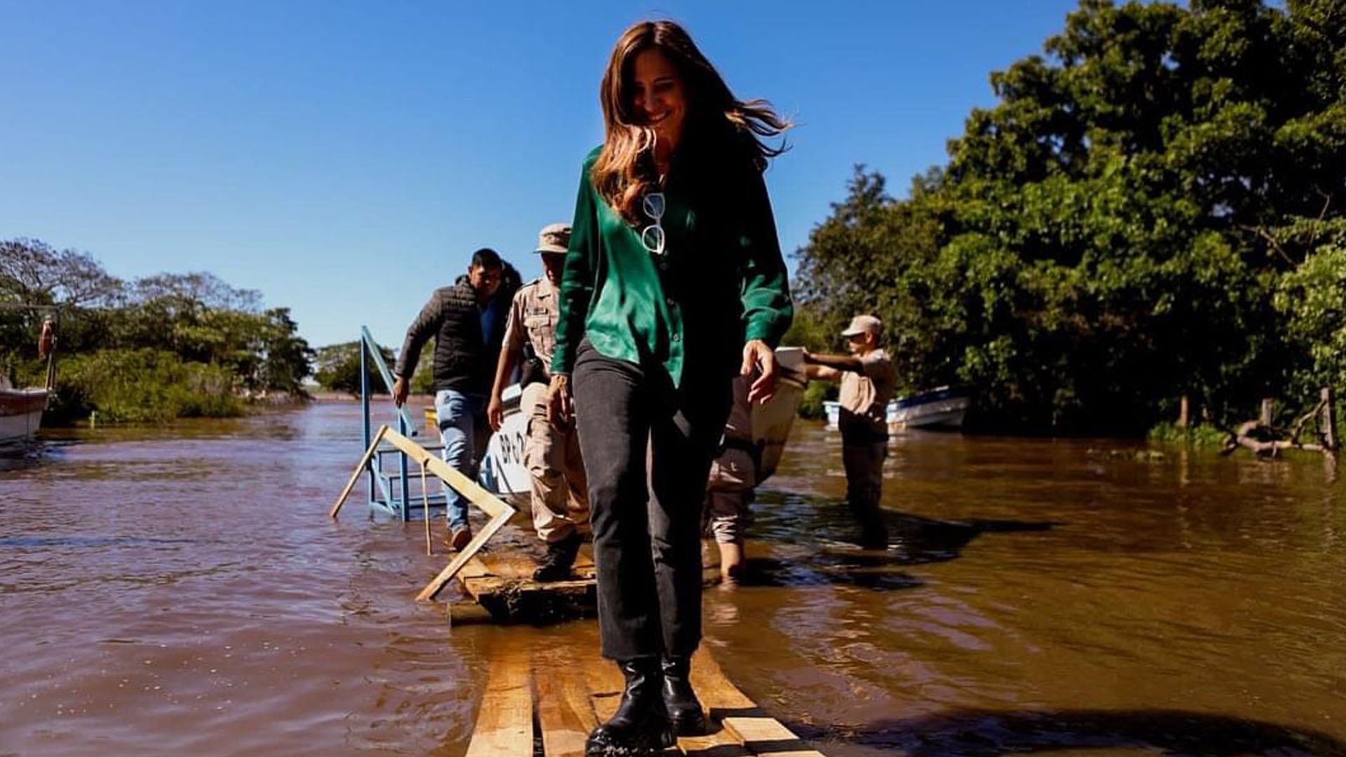 la ministra caminando sobre un camino de madera sobre el agua llegando a la Isla afectada por el temporal.